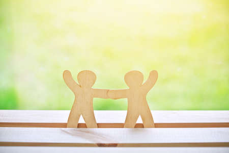 Wooden little men holding hands. Symbol of friendship, love and teamworkの写真素材
