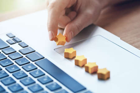 hand gives five stars rating as product feedback with laptopの写真素材