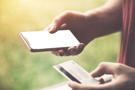 Hands holding credit card and using smartphone. Online shopping. Blank screen for site or textの写真素材