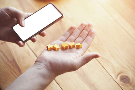 hand gives five stars rating as product feedback with smart phoneの写真素材