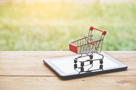 digital tablet  with trolley as symbol of online shopping and payingの写真素材