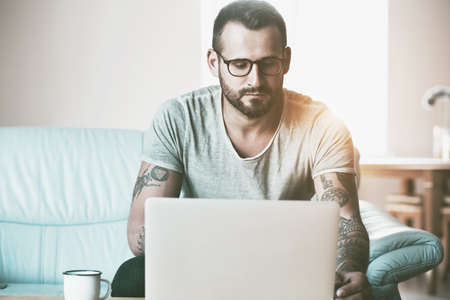 man with laptop typing at coffee table
