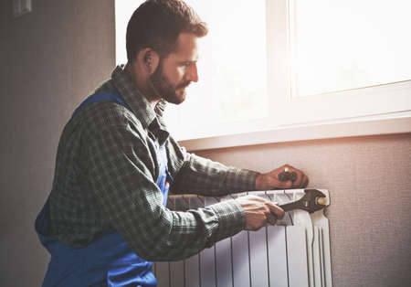 service man with wrench near radiatorの写真素材