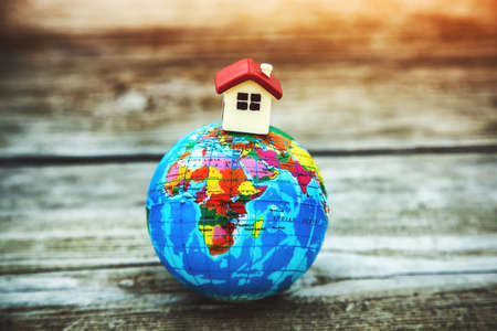 Little toy house on earth planet model. Motherland, ecology, property concept. Symbol of homeの写真素材