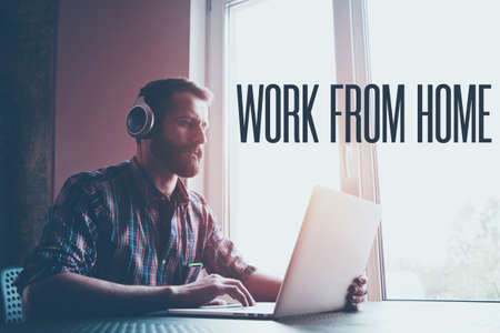 Man  in headphones with laptop and text Work from home. Home isolation and quarantine during coronavirus covid-19 pandemic.の写真素材
