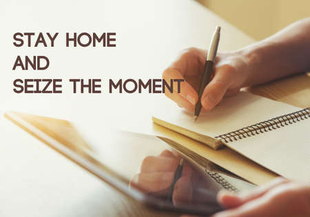 Hand writing with pen with digital tablet and text Stay home and seize the moment. Home isolation and quarantine during coronavirus covid-19 pandemic.の写真素材