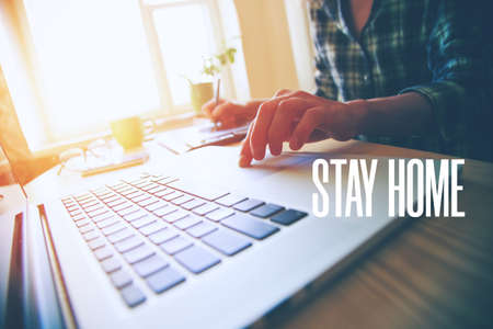 Home office with freelancer hands with laptop and text Stay home. Home isolation and quarantine during coronavirus covid-19 pandemic.の写真素材