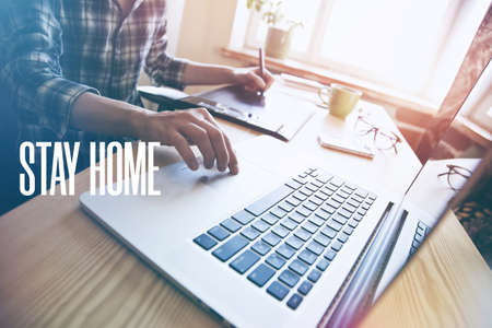 Home office with freelancer hands with laptop and text Stay home. Home isolation and quarantine during coronavirus covid-19 pandemic.の写真素材