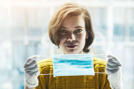 Portrait of woman holding medical mask. Protection from catching disease or allergy. Pandemic of coronavirus concept.の写真素材
