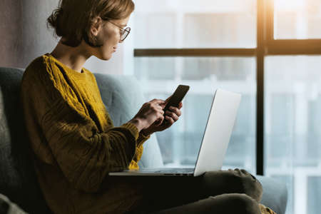 Woman working with phone at home quarantine in morning light. Stay at home campaign.の写真素材
