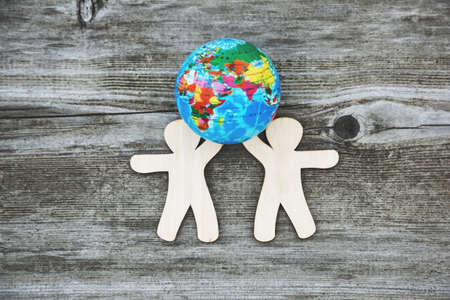 Wooden little men holding earth planet. People of the world holding the globe. の写真素材