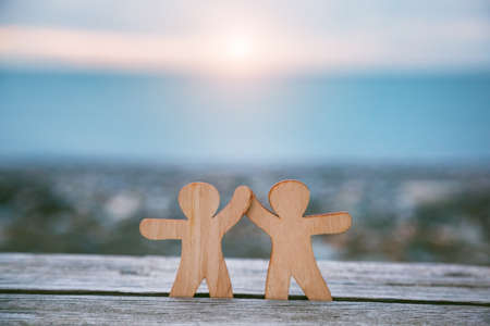 Wooden little men holding hands. Teamwork, friendship and love concept