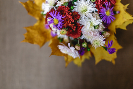 Bouquet of flowers and yellow autumn leaves on a fabric blurred background. Top viewの写真素材