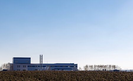 Agricultural factory on background of clear sky and  field in the foregroundの写真素材