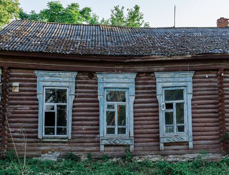 Facade of an abandoned wooden house with carved windowsの写真素材