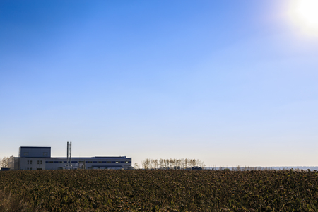 Agricultural factory on background of clear sky and  field in the foregroundの写真素材