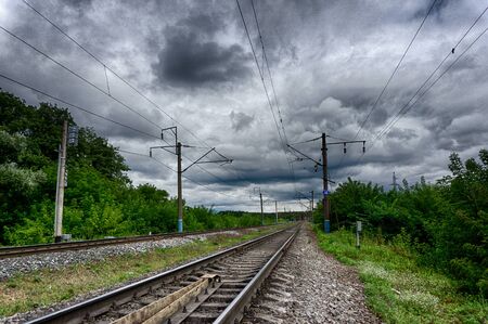 view of the railway receding into the distance through the trees. Overcast sky. hdrの写真素材