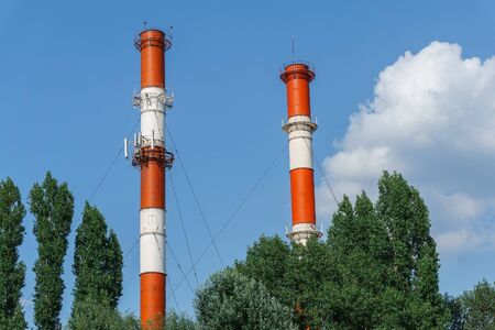 Red and white factory pipes in the cloudy skyの写真素材