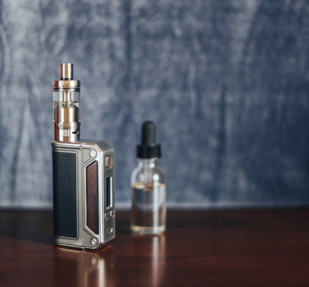 Vape devices, E cigarette for vaping, liquid in the bottle on wooden table