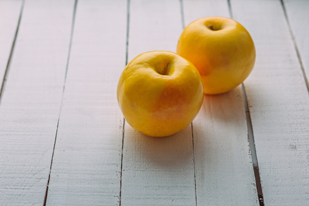 two yellow fresh apples on white rustic wooden background. copy spaceの写真素材