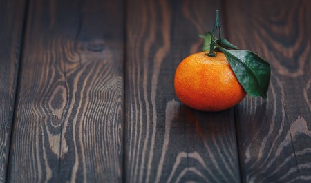 fresh juicy ripe tangerine with leaves on wooden background closeup. health  organic vegetarian diet concept. winter mandarin. copy spaceの写真素材