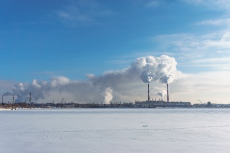 Power station with pipes of which poured smoke on a frozen river. Free copyspace for text. Horizontal image.の写真素材