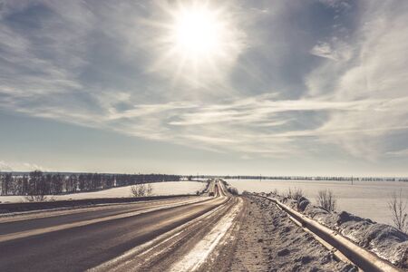 Asphalt road in snowy winter on beautiful frosty sunny day. Retro toned pictureの写真素材