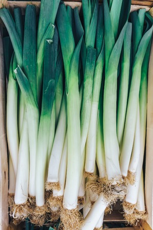 Stalks of leeks, green vegetables, local market produce in a box close up image. Top view. vegetarian, raw food, vitamins, healthy foodの写真素材