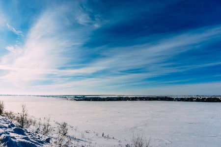 Majestic Winter landscape with beautiful colourful sky, snow and little village in far away. Copy...