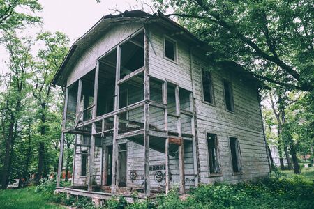 Old abandoned rustic wooden mansion house among green treesの写真素材