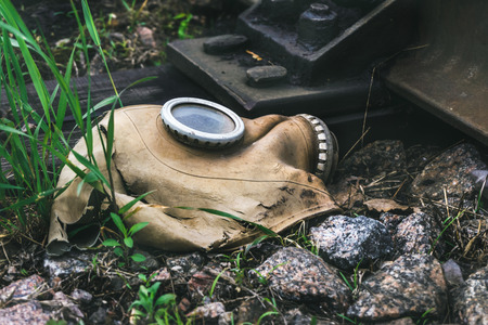 Ragged gas mask among stones and grass  near railroadの写真素材