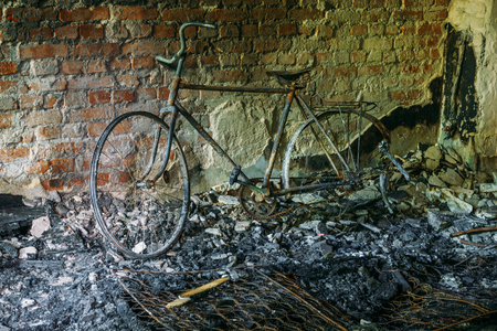 Burnt-out bicycle in old abandoned burnt houseの写真素材