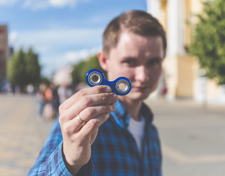 Young hipster man showing to camera fidget spinner, focus on spinnerの写真素材