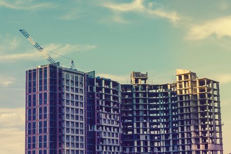 Large modern building is under construction. Construction industry, housing development, crane. Image in warm tonesの写真素材