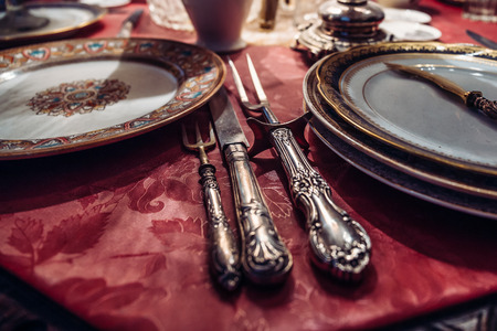 Antique dinner sett on table. Vintage Old Utensils: Forks, Plates, Spoons and Knifes, toned