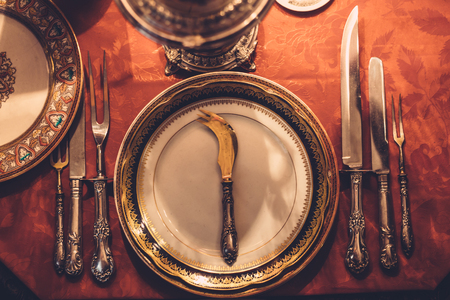 Vintage table set on red table, vintage plates and silver knives, top view, tonedの写真素材