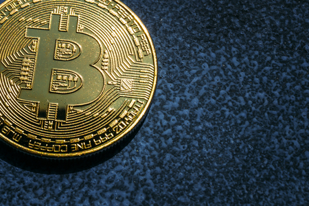 Close-up of Bitcoin golden coin on blue background with copy space, toned