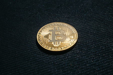 Golden coin of Bitcoin on black textured backgroundの写真素材