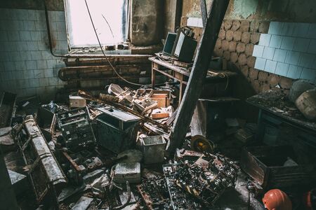 Room with old rubbish in an abandoned factory, construction helmets are lying on the floor,...