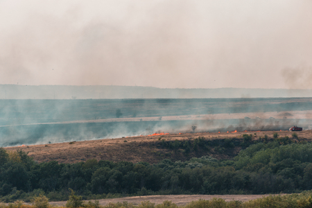 Burning grass in the fields and smoke from the fire rises, natural summer fires in the Rostov region, Russiaの写真素材