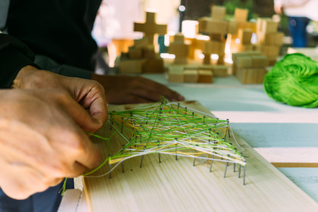 Close-up of male hands making a picture of threads and nails, soothing trending hobby, selective...