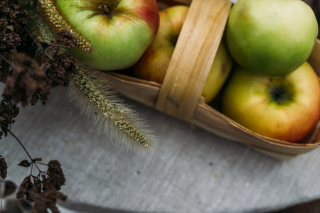 Fresh apples in a wicker basket on a table, selective focus, top view, tonedの写真素材