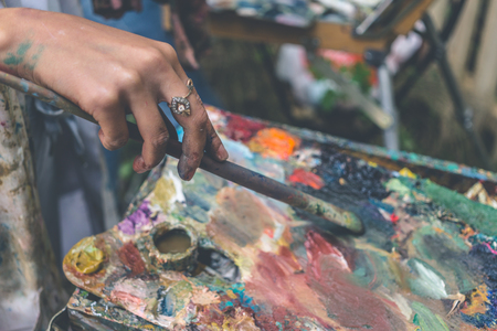 Artist paints picture by oil paint brush in hand with palette, selective focus, close up, tonedの写真素材