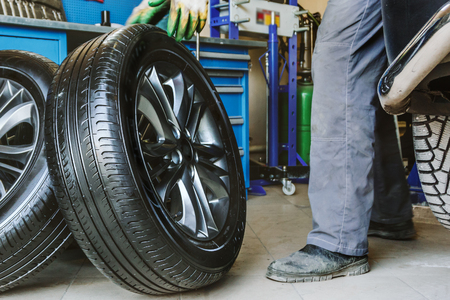 Mechanic changes car wheel in auto repair shop, tonedの写真素材