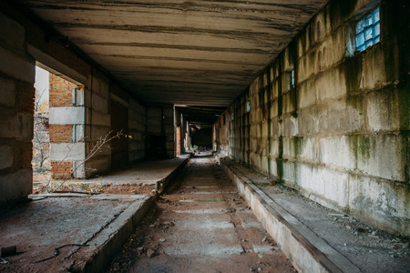 Dark scary corridor in abandoned industrial ruined brick factory, creepy interior, perspective tonedの写真素材