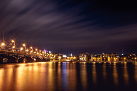 Illuminated Chernavsky bridge at night, view to right bank or downtown of Voronezh city, dramatic cityscape with reflection in waterの写真素材