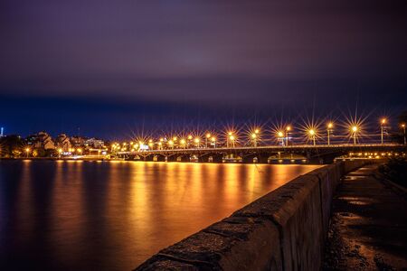 Illuminated Chernavsky bridge at night, view to right bank or downtown of Voronezh city, dramatic cityscape with reflection in waterの写真素材