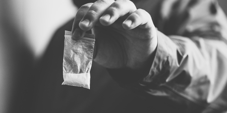 Drug dealer selling drugs junkie. Drug abuse concept and overdose concept. Mans hand holds plastic...