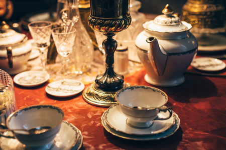 Set of vintage antique dinnerware on red table, tonedの写真素材