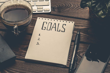 Goals list on notepad on work table, motivation strategy concept, retro toned